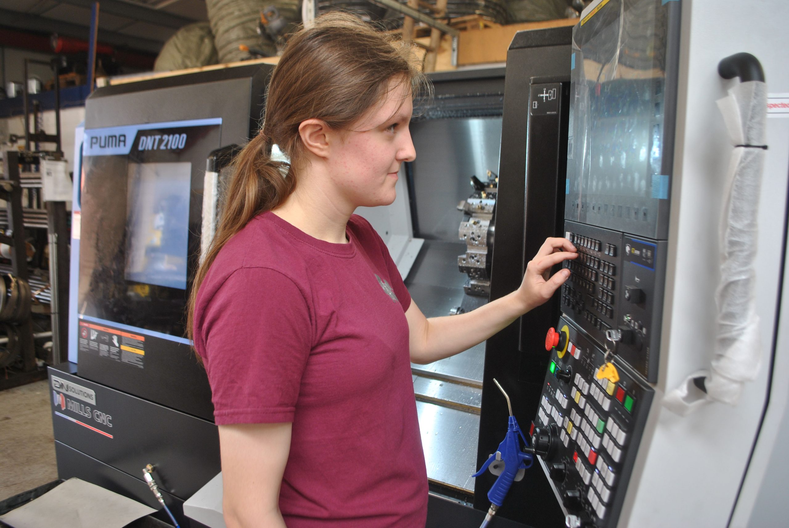 Female CNC Operator at controls of DNT 2100 lathe