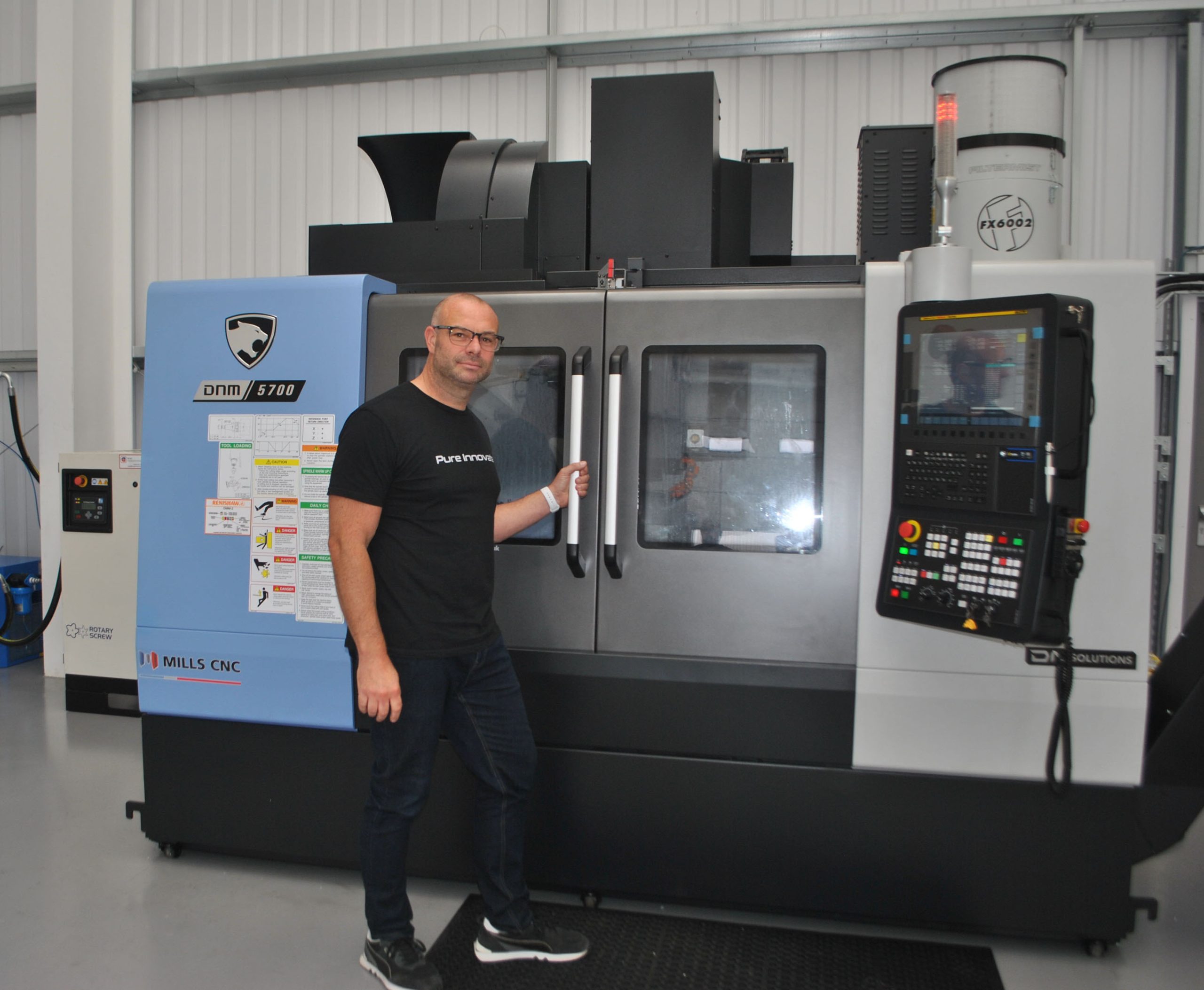 Operator standing by the doors of a DN Solutions DNM 5700 machining centre