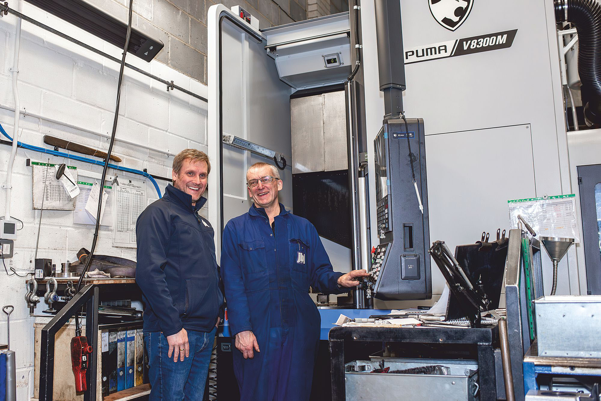 Operators in front of a DN Solutions Puma V8300M vertical turning lathe