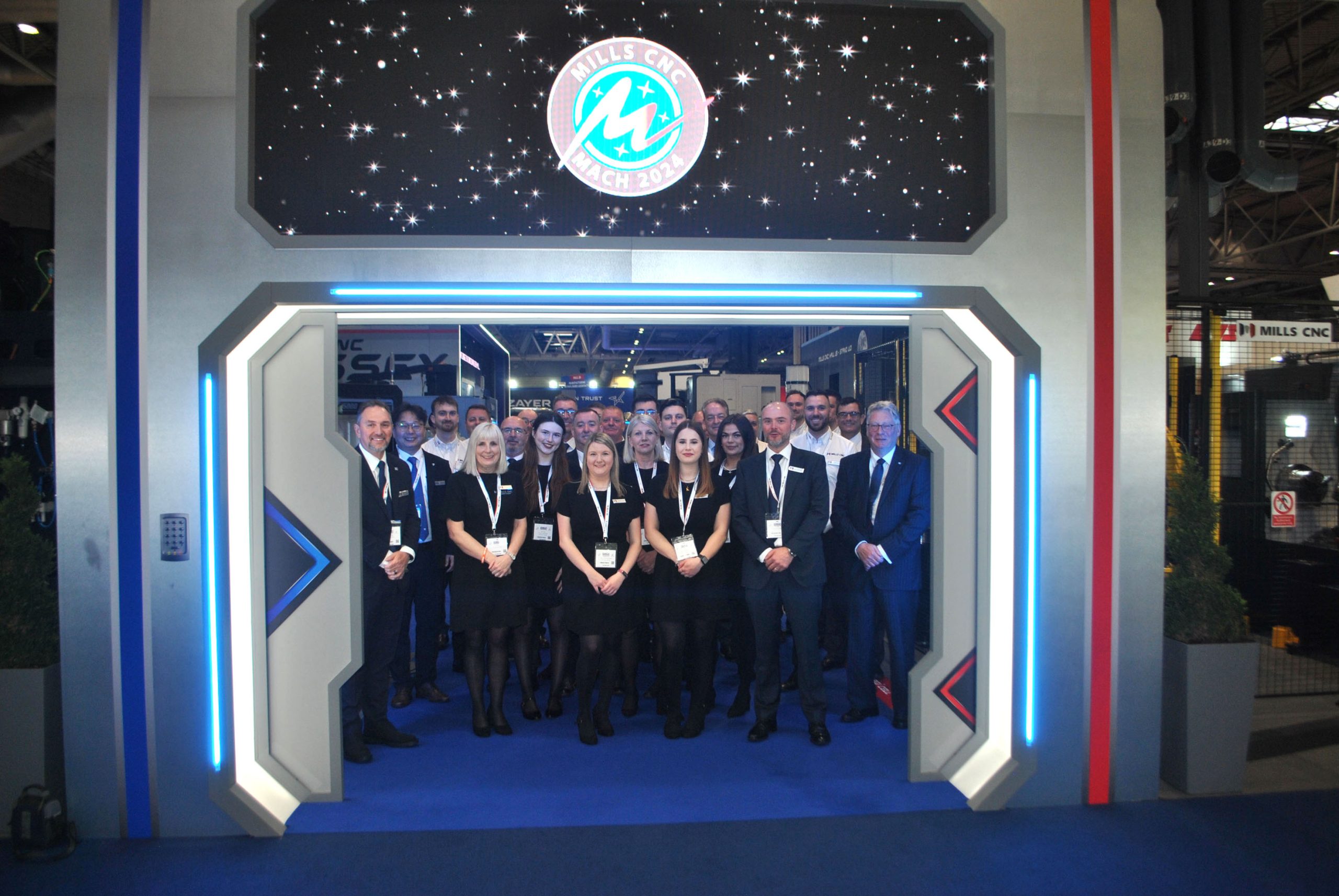 Mills CNC team stand under the entrance to their stand at MACH 2024