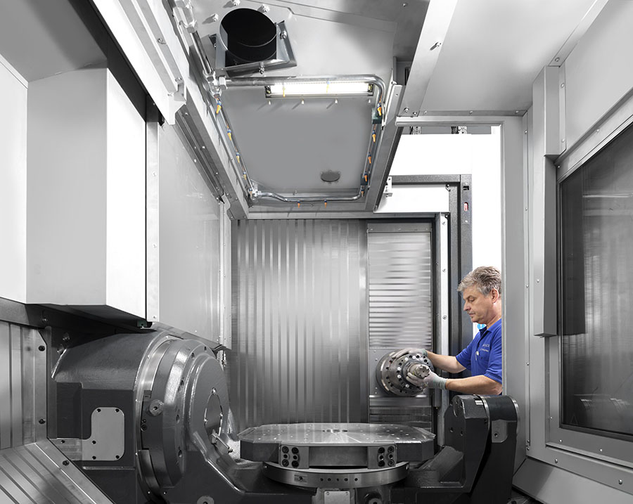 An operator with a Heller HF 5500 FLEX horizontal simultaneous 5-axis mill-turn machine